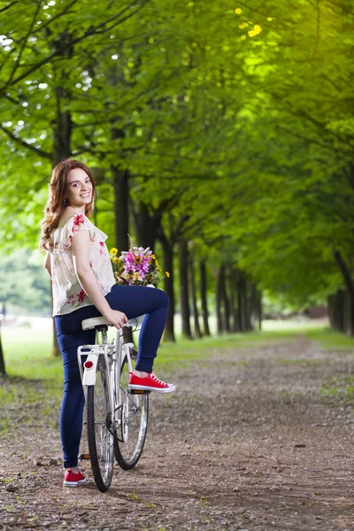 Mujer de pie con una bicicleta vintage en el parque —  Fotos de Stock