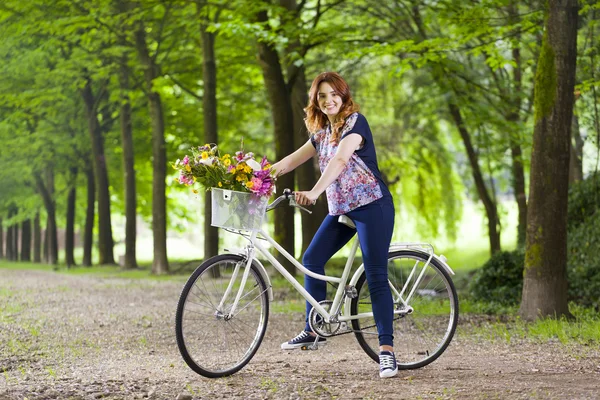 Mulher de pé com uma bicicleta vintage no parque — Fotografia de Stock