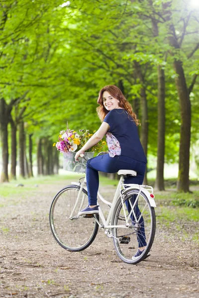 Mujer de pie con una bicicleta vintage en el parque —  Fotos de Stock