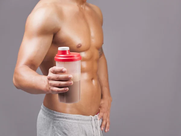 Muskulös man innehar en shaker med protein — Stockfoto