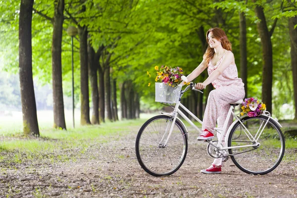 Kobieta stojąc z rocznika rowerów w parku — Zdjęcie stockowe