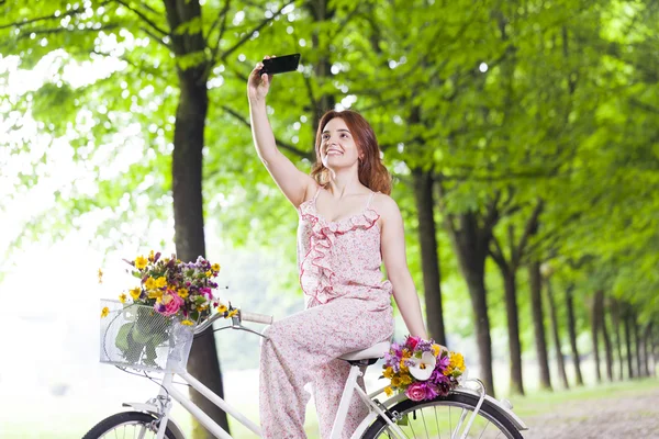 Vacker flicka på cykel med en selfie — Stockfoto