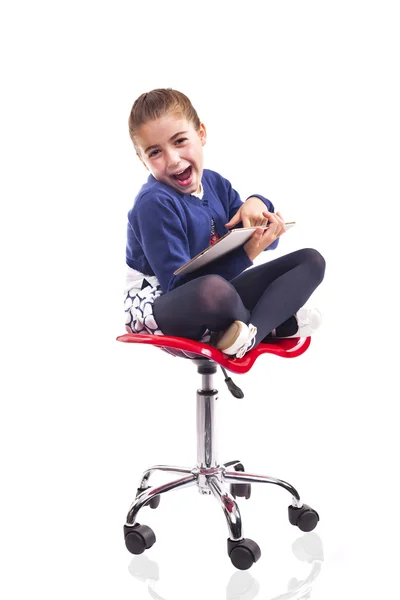 Lány ül egy széken, és egy tabletta számítógép segítségével — Stock Fotó