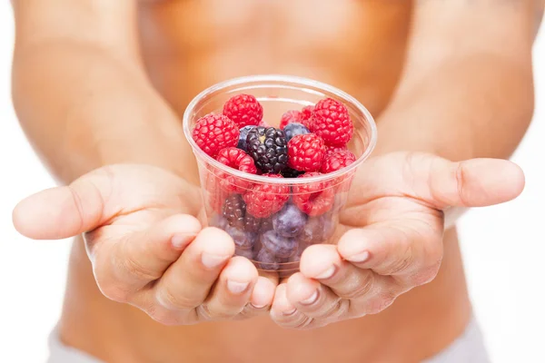 Fit man holding a bowl of fresh red fruits — Stock Photo, Image