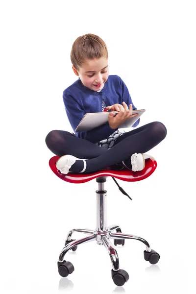 Chica sentada en una silla y usando una tableta — Foto de Stock