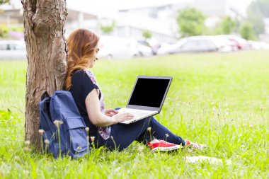 dizüstü bilgisayar kullanan çimenlerin üzerinde öğrenci kız