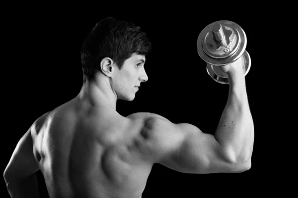 Вид сзади на фитнес-человека, поднимающего тяжести на черном фоне — стоковое фото