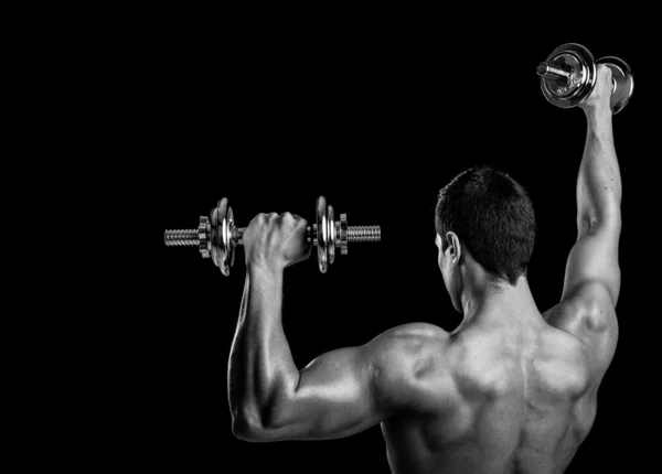 Visão traseira de um homem de fitness levantando pesos no fundo preto — Fotografia de Stock