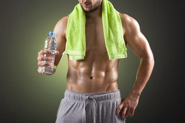 Fitness-Mann hält eine Flasche Frischwasser auf schwarzem Hintergrund — Stockfoto