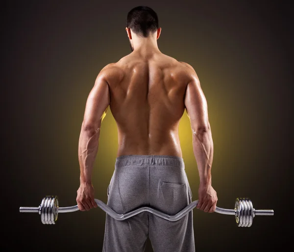 Visão traseira de um homem de fitness levantando pesos com barra de curl — Fotografia de Stock