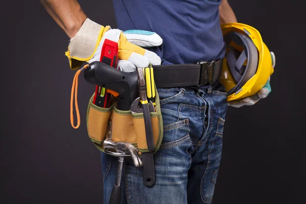 Nahaufnahme eines Arbeiters mit Werkzeuggurt und Helm gegen schwarzen Rücken — Stockfoto