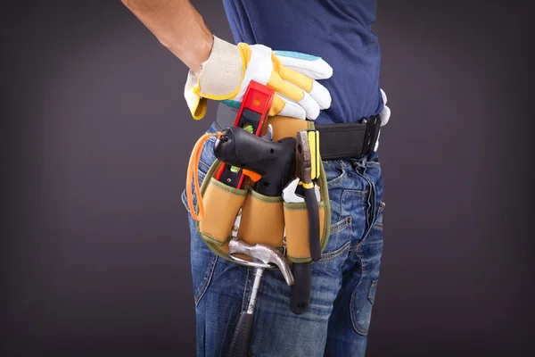 Close up of a worker with toolbelt and helmet against black back — Stock Photo, Image