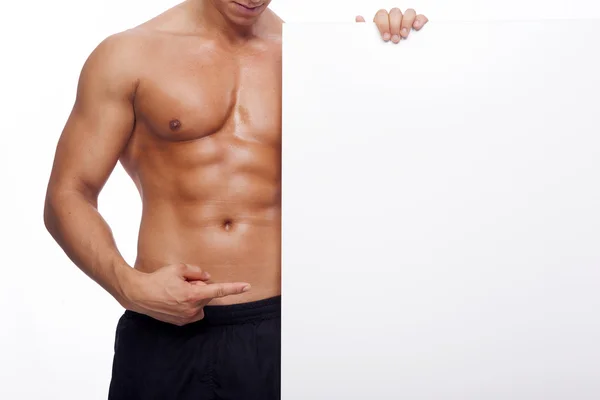 Fitness man pointing to a white banner — Stock Photo, Image