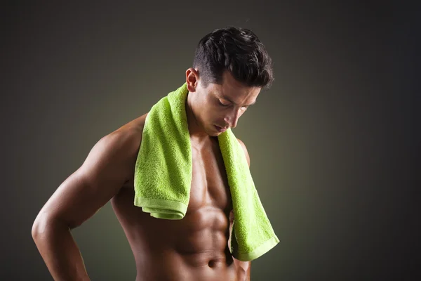 Uomo atletico con un asciugamano verde su sfondo nero — Foto Stock