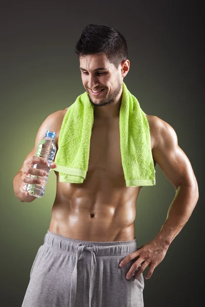 Sonriente hombre de fitness sosteniendo una botella de agua dulce en bac negro —  Fotos de Stock