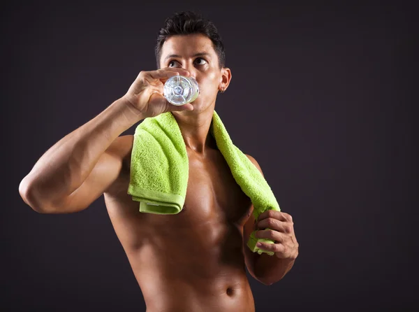 Homem de fitness bebendo uma garrafa de água doce no fundo preto — Fotografia de Stock