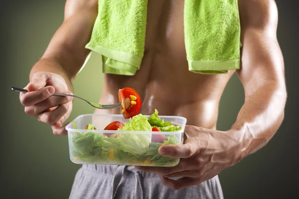 Fitness man holding a bowl of fresh salad — Stock Photo, Image