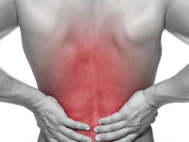 Arkaya bakan genç bir adam acı içinde sırtını tutuyor, izole bir şekilde.