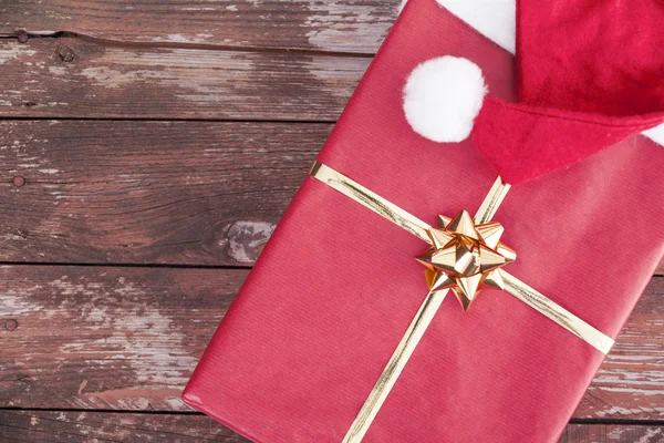 Santa claus hat and gift box on a wooden background — Stock Photo, Image