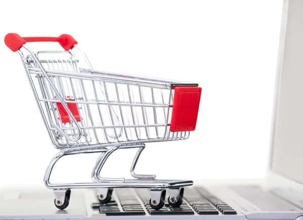 Shopping cart over a laptop computer, isolated on white backgrou — Stock Photo, Image