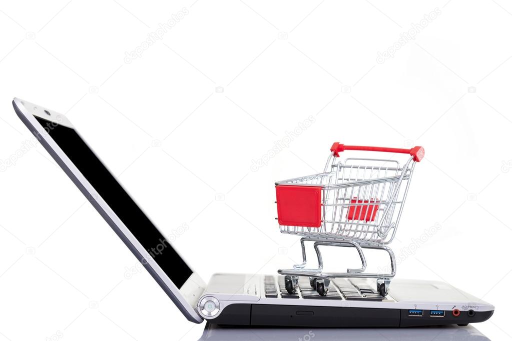 Shopping cart over a laptop computer, isolated on white background