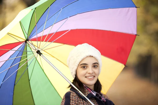 Krásná dívka stojící s vícebarevné deštník v parku — Stock fotografie