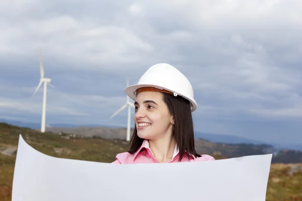 Female engineer holding a blueprint at wind turbine site — Stock Photo, Image