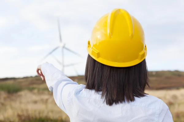 Engenheira feminina apontando para moinhos de vento — Fotografia de Stock
