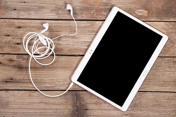 Tablet with earphones on wood — Stock Photo, Image