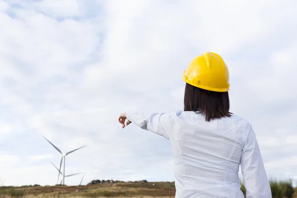 Ingénieur femelle pointant vers les éoliennes — Photo