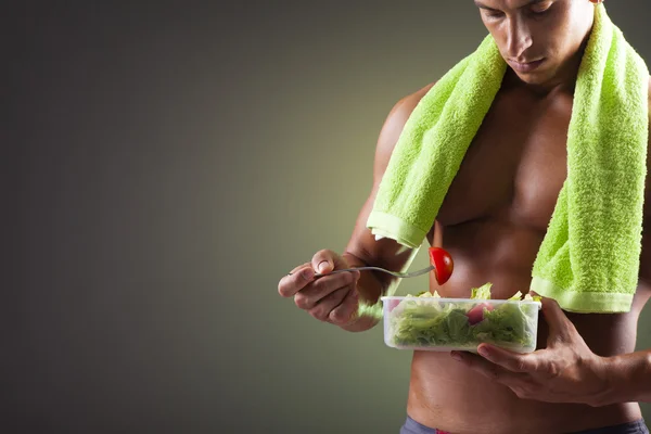 Strong man holding a bowl of fresh salad — Stock Photo, Image