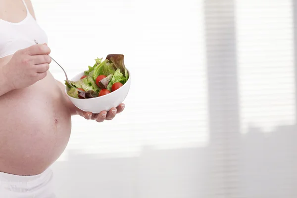 Femme enceinte tenant un bol de salade — Photo