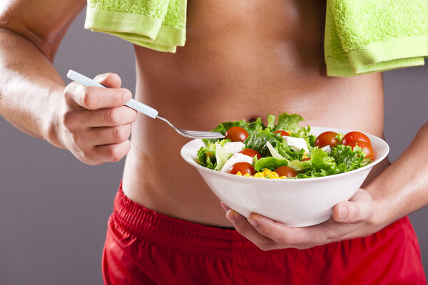 Fit man holding a bowl of fresh salad