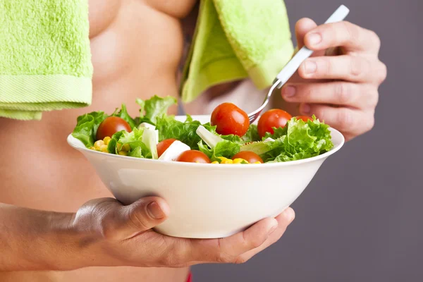 Fit man holding a bowl of fresh salad — Stock Photo, Image