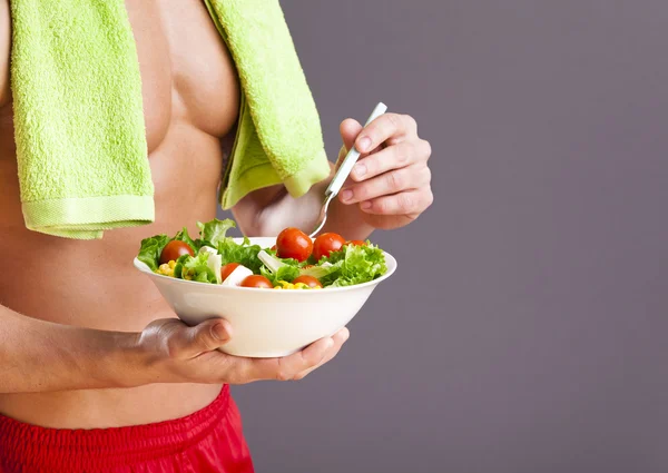 Fit man holding a bowl of fresh salad — Stock Photo, Image