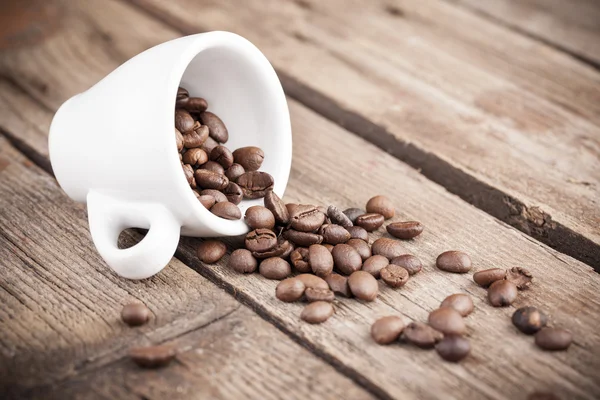 Taza con granos de café sobre fondo de madera — Foto de Stock