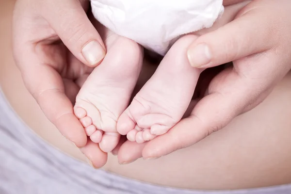 Hände der Mutter halten den Fuß des Babys — Stockfoto