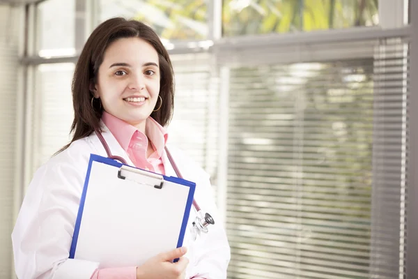 Smiling female doctor holding a clipboard — Stock Photo, Image