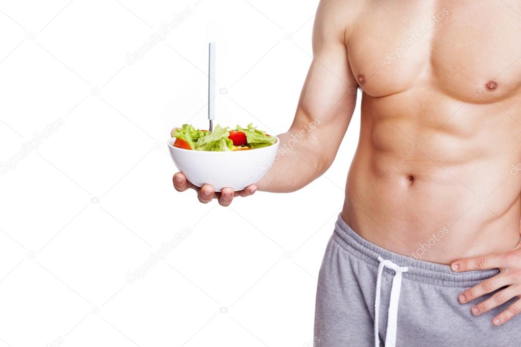 Muscular man holding a bowl of salad