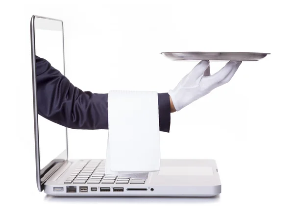 Waiter hand holding a silver tray through a laptop — Stock Photo, Image