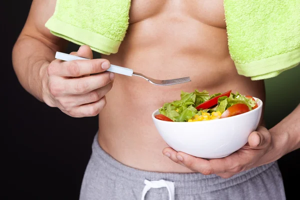 Fit man holding a bowl of fresh salad — Stock Photo, Image