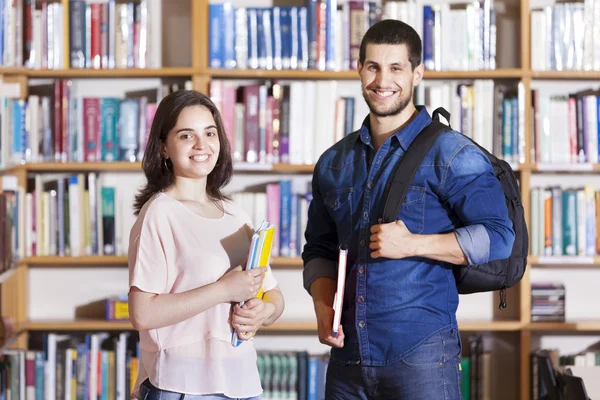 Felices estudiantes sonrientes en la biblioteca — Foto de Stock