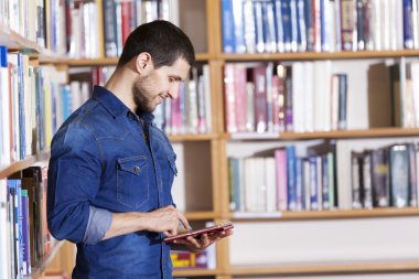 bir tablet bilgisayar tutan erkek öğrenci