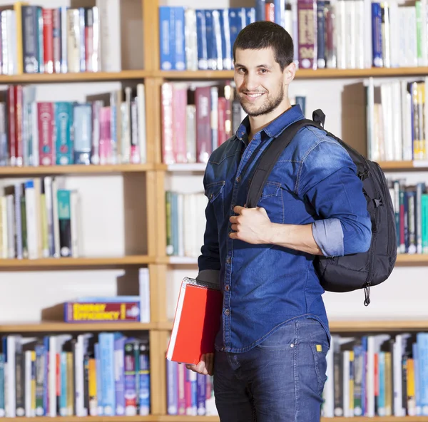 Estudante do sexo masculino sorrindo na biblioteca — Fotografia de Stock