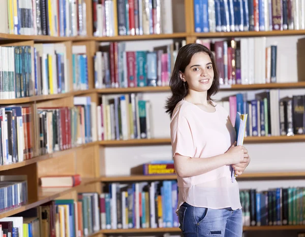 Estudante feminina segurando cadernos na biblioteca — Fotografia de Stock