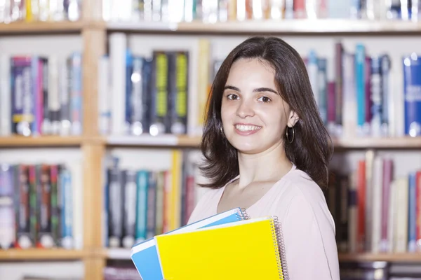 Female student holding books at the library — Stock Photo, Image