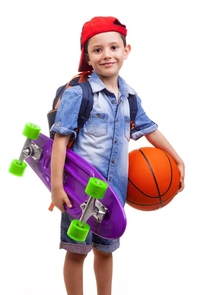 Menino da escola segurando um skate e uma bola de basquete — Fotografia de Stock