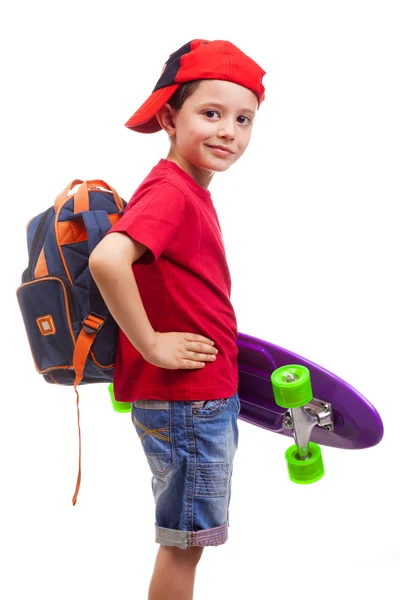 Leende schoolkid stående med skateboard och ryggsäck — Stockfoto