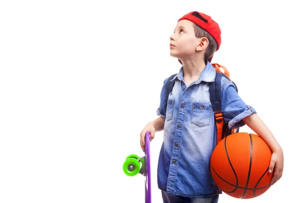 School jongen holding een skateboard en een basketbal — Stockfoto