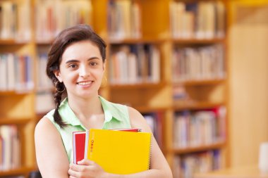 Kütüphanede dizüstü bilgisayarlar ile ayakta kız öğrenci